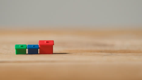 Home-Buying-Concept-With-Red-Blue-And-Green-Plastic-Model-Of-Houses-On-Wooden-Surface-