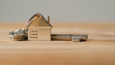 Hauskaufkonzept-Mit-Person,-Die-Schlüssel-Auf-Hausförmigem-Schlüsselring-Von-Der-Holzoberfläche-Abholt