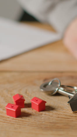 Vertical-Video-Home-Buying-Concept-With-Keys-On-House-Shaped-Keyring-And-Person-Checking-Finances