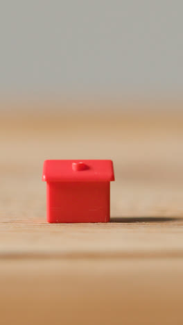 Vertical-Video-Home-Buying-Concept-With-Red-Plastic-Model-Of-House-On-Wooden-Surface