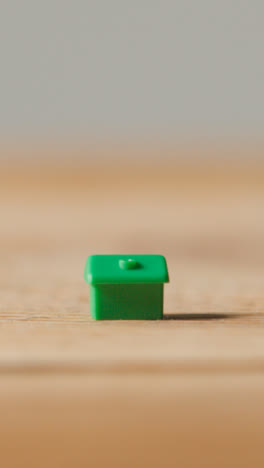 Vertical-Video-Home-Buying-Concept-With-Green-Plastic-Model-Of-House-On-Wooden-Surface