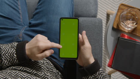 Overhead-Shot-Of-Person-At-Home-Shopping-Online-Looking-At-Green-Screen-On-Mobile-Phone
