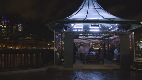 Gente-Sentada-En-Un-Café-Junto-Al-Río-Támesis-En-La-Orilla-Sur-De-Londres-Por-La-Noche