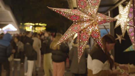 Cerrar-Puesto-De-Venta-De-Luces-O-Decoraciones-En-Forma-De-Estrella-En-El-Mercado-De-Navidad-En-El-South-Bank-De-Londres-Por-La-Noche