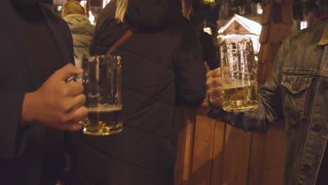 Cerca-De-Gente-Bebiendo-Cerveza-En-Los-Puestos-Del-Mercado-Navideño-De-Frankfurt-En-Birmingham,-Reino-Unido-Por-La-Noche