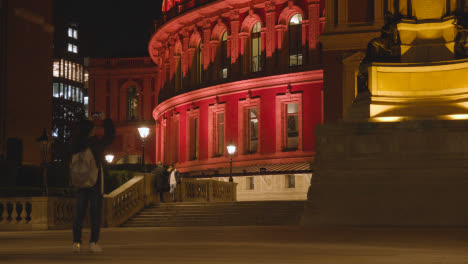 Persona-Con-Teléfono-Tomando-Una-Foto-Del-Exterior-Del-Royal-Albert-Hall-En-Londres-Reino-Unido-Iluminado-Por-La-Noche