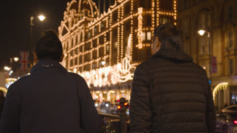 People-Walking-Towards-Exterior-Of-Harrods-Department-Store-In-London-Decorated-With-Christmas-Lights