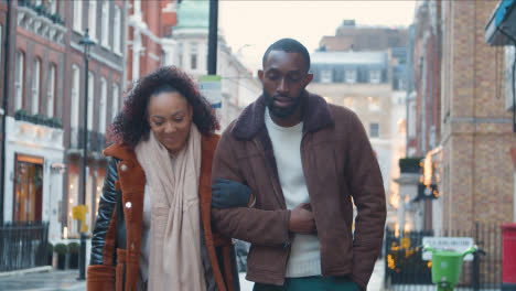Couple-Walking-Arm-In-Arm-Through-Street-On-Winter-Visit-To-London-1