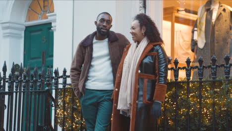 Paar-Außerhalb-Bekleidungsgeschäft-Dekoriert-Für-Weihnachten-Auf-Shopping-Trip-Nach-London