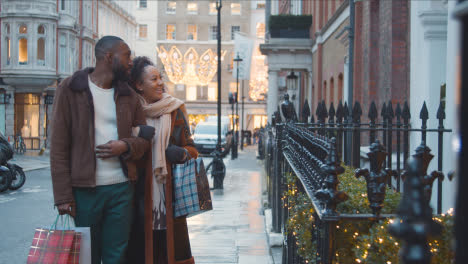 Couple-Walking-Arm-In-Arm-Through-Street-On-Christmas-Shopping-Trip-To-London-2