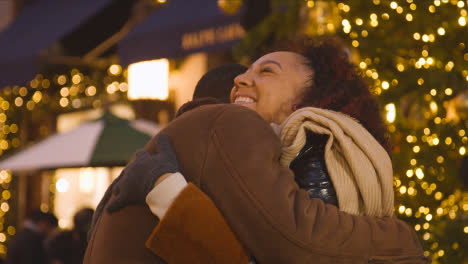 Loving-Couple-Hugging-Walking-Along-Street-On-Christmas-Shopping-Trip-To-London-
