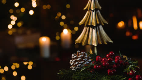 Close-Up-Of-Christmas-Decorations-At-Home-With-Pine-Cone-And-Holly-On-Table