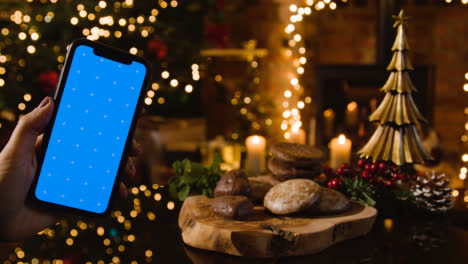 Weihnachten-Zu-Hause-Mit-Traditionellen-Deutschen-Weihnachtslebkuchen-Und-Person-Mit-Blauem-Bildschirmhandy