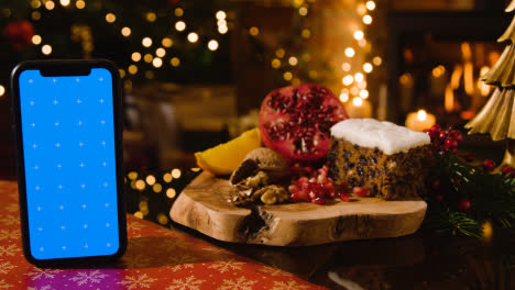 Comida-Navideña-En-Casa-Y-Pastel-Tradicional-De-Navidad-Y-Teléfono-Móvil-Con-Pantalla-Azul