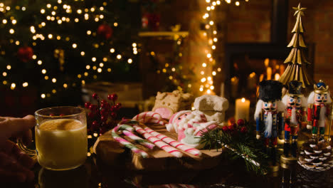 Navidad-En-Casa-Con-Una-Persona-Bebiendo-Un-Vaso-De-Ponche-De-Huevo,-Bastones-De-Caramelo-Y-Galletas