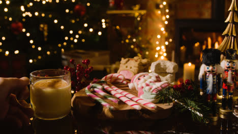 Navidad-En-Casa-Con-Una-Persona-Bebiendo-Un-Vaso-De-Ponche-De-Huevo,-Bastones-De-Caramelo-Y-Galletas