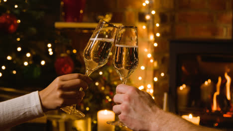 Nahaufnahme-Eines-Paares,-Das-Zu-Hause-Weihnachtstoast-Mit-Champagner-Vor-Dem-Feuer-Macht