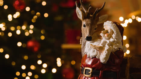 Close-Up-Of-Christmas-Decoration-Of-Santa-With-Rudolph-At-Home-Tree-And-Lights