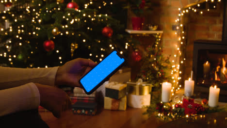 Weihnachten-Zu-Hause-Mit-Einer-Person,-Die-Auf-Ein-Bluescreen-handy-Schaut-2