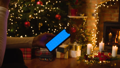 Navidad-En-Casa-Con-Una-Persona-Mirando-El-Teléfono-Móvil-Con-Pantalla-Azul-3