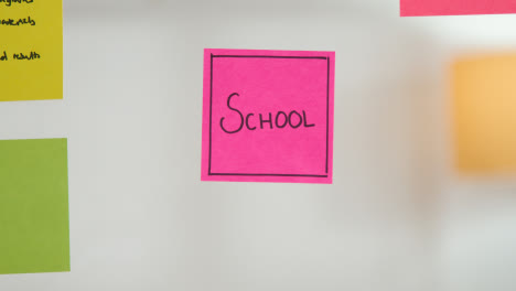 Close-Up-Of-Woman-Putting-Sticky-Note-With-School-Written-On-It-Onto-Transparent-Screen-In-Office-1