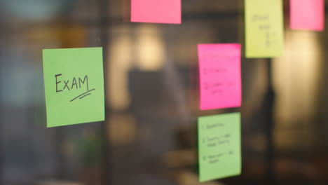 Close-Up-Of-Woman-Putting-Sticky-Note-With-Exam-Written-On-It-Onto-Transparent-Screen-In-Office-1