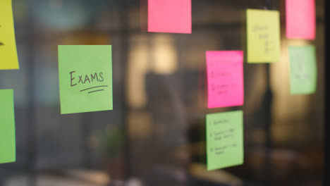Close-Up-Of-Woman-Putting-Sticky-Note-With-Exams-Written-On-It-Onto-Transparent-Screen-In-Office-1