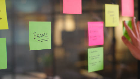Close-Up-Of-Woman-Putting-Sticky-Note-With-Exams-Written-On-It-Onto-Transparent-Screen-In-Office-2