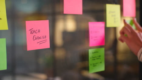 Close-Up-Of-Woman-Putting-Sticky-Note-With-Teach-English-Written-On-It-Onto-Transparent-Screen-In-Office-3
