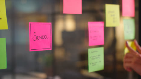 Close-Up-Of-Woman-Putting-Sticky-Note-With-School-Written-On-It-Onto-Transparent-Screen-In-Office-1