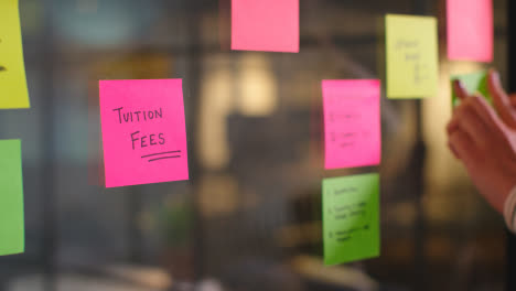 Close-Up-Of-Woman-Putting-Sticky-Note-With-Tuition-Fees-Written-On-It-Onto-Transparent-Screen-In-Office-2