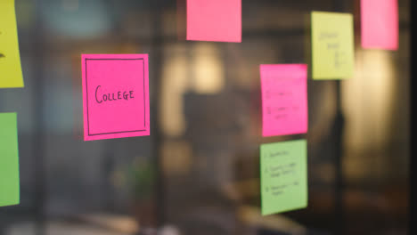 Close-Up-Of-Woman-Putting-Sticky-Note-With-College-Written-On-It-Onto-Transparent-Screen-In-Office-2