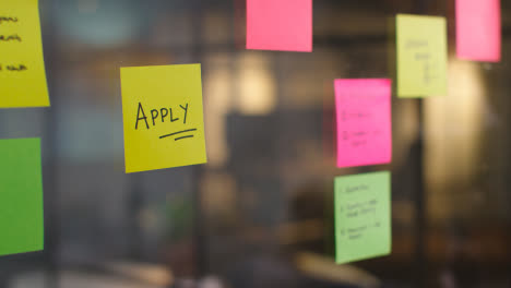 Close-Up-Of-Woman-Putting-Sticky-Note-With-Apply-Written-On-It-Onto-Transparent-Screen-In-Office-2