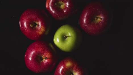 Overhead-Studio-Shot-Of-Hand-Replacing-Red-And-Green-Apples-Revolving-Against-Black-Background