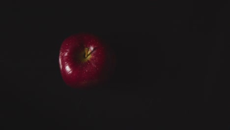 Overhead-Studio-Shot-Of-Hand-Replacing-Green-Apple-Next-To-Red-Apple-Revolving-Against-Black-Background