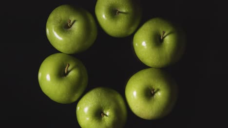 Obenliegende-Studioaufnahme-Des-Kreises-Grüner-Äpfel,-Die-Sich-Vor-Schwarzem-Hintergrund-Drehen