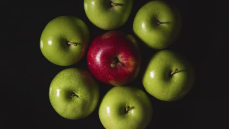 Foto-De-Estudio-Superior-De-Manzana-Roja-En-Un-Círculo-De-Manzanas-Verdes-Girando-Sobre-Fondo-Negro