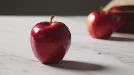 Studioaufnahme-Einer-Papiertüte-Mit-Roten-Äpfeln-Auf-Einer-Küchenoberfläche-Aus-Marmor