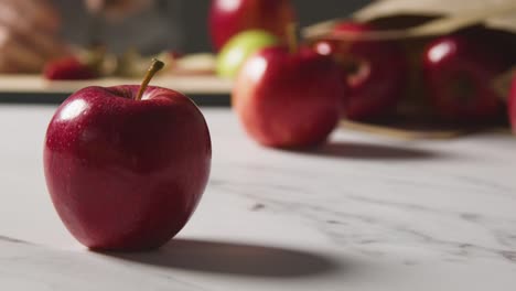 Nahaufnahme-Eines-Mannes,-Der-Rote-Äpfel-Aus-Einer-Papiertüte-Mit-Roten-Äpfeln-Auf-Einer-Marmorküchenoberfläche-Schneidet