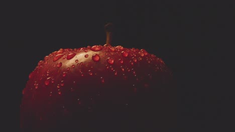 Primer-Plano-De-Estudio-De-Manzana-Roja-Con-Gotas-De-Agua-Girando-Sobre-Fondo-Negro