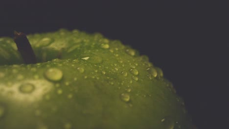 Macro-Studio-Shot-Of-Green-Apple-With-Water-Droplets-Revolving-Against-Black-Background