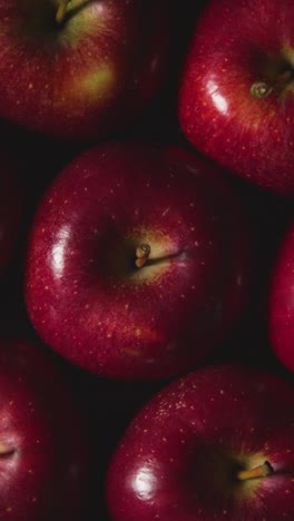 Vertical-Video-Overhead-Studio-Shot-Of-Red-Apples-Revolving-Against-Black-Background