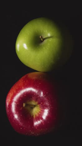 Fotografía-De-Estudio-De-Video-Vertical-De-Manzanas-Verdes-Y-Rojas-Girando-Sobre-Fondo-Negro