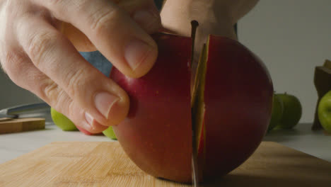Close-Up-Of-Man-Cutting-Fresh-Apples-On-Chopping-Board