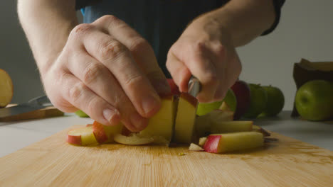 Close-Up-Of-Man-Cutting-Fresh-Apples-On-Chopping-Board-2