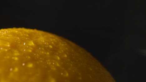 Macro-Studio-Shot-Of-Orange-With-Water-Droplets-Revolving-Against-Black-Background