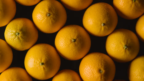 Overhead-Studio-Shot-Of-Oranges-Being-Sprayed-With-Water-Revolving-Against-Black-Background