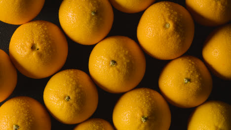 Overhead-Studio-Shot-Of-Oranges-With-Water-Droplets-Against-Black-Background
