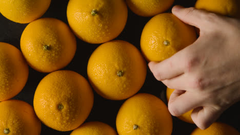 Overhead-Studioaufnahme-Einer-Hand,-Die-Orange-Auf-Einen-Sich-Drehenden-Schwarzen-Hintergrund-Ersetzt-1