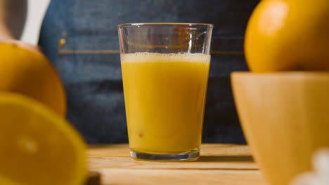 Nahaufnahme-Eines-Mannes,-Der-Frischen-Orangensaft-In-Ein-Glas-Mit-Eis-Gießt,-Mit-Orangen-Im-Vordergrund-1